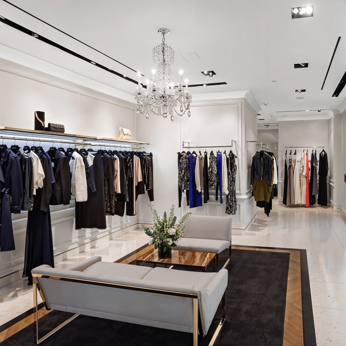 Elegant boutique interior featuring installed 1/4 Round Cove Crown Molding along the ceiling, with clothing displays, a crystal chandelier, recessed lighting, and a modern seating area.